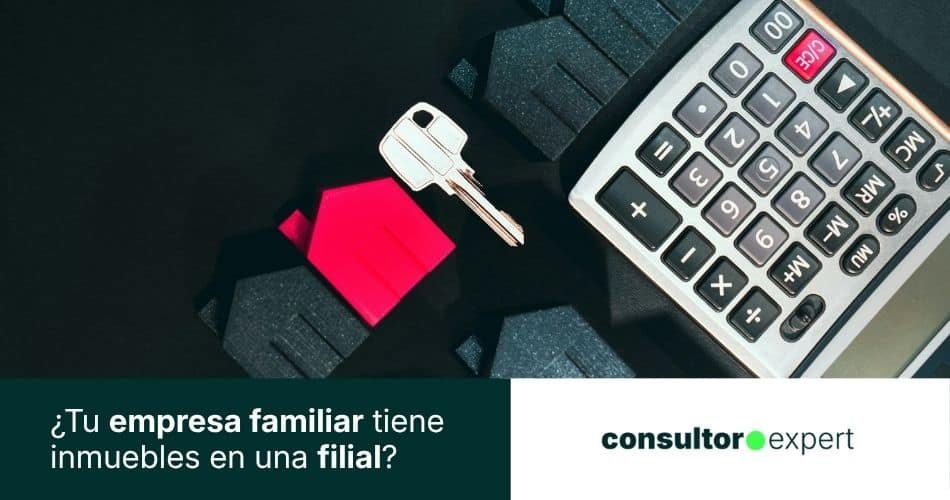 Casas en miniatura con calculadora y llave representando la fiscalidad de inmuebles en empresa familiar